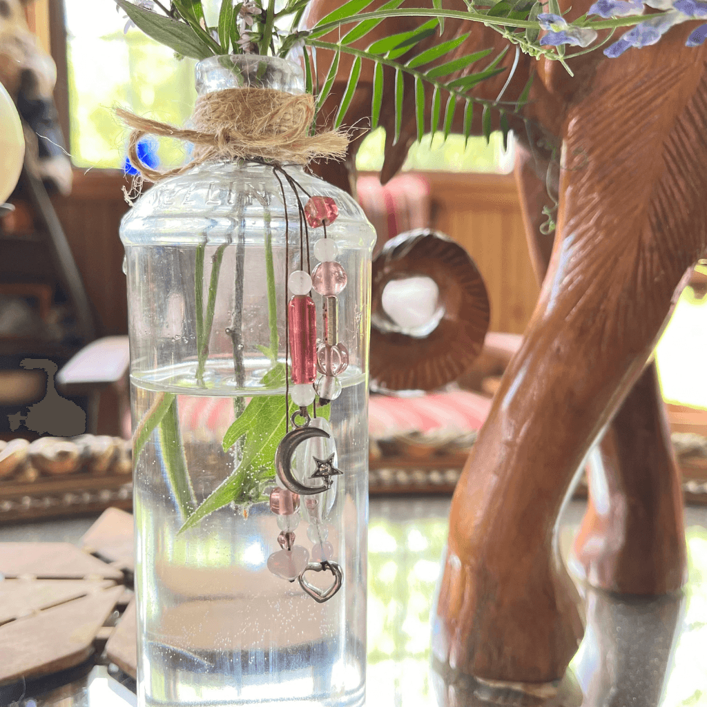 Vintage L.F. Medicine Co. bottle found in the Aroostook River, decorated with pink beads, moon and heart charms, and used as a flower vase