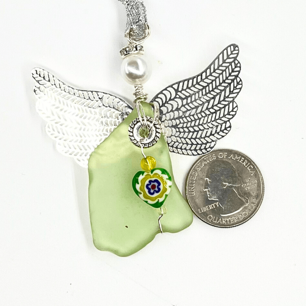 Uranium glass angel ornament with heart charm beside a quarter for scale