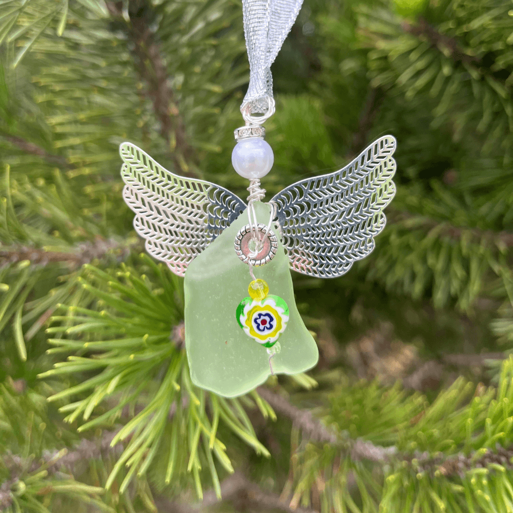 Angel ornament hanging from a pine tree branch with uranium glass and yellow bead accents