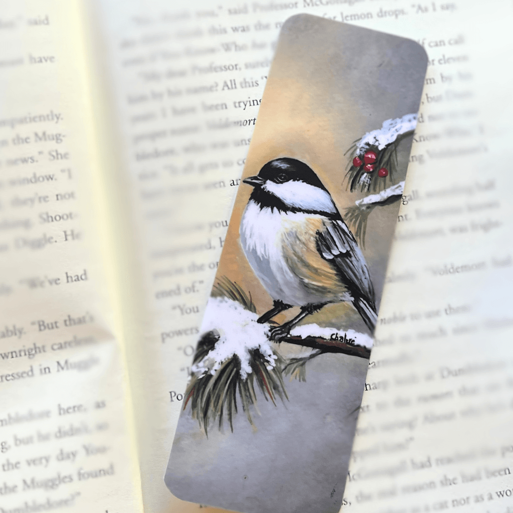Handmade Winter Chickadee bookmark without tassel resting in a book.