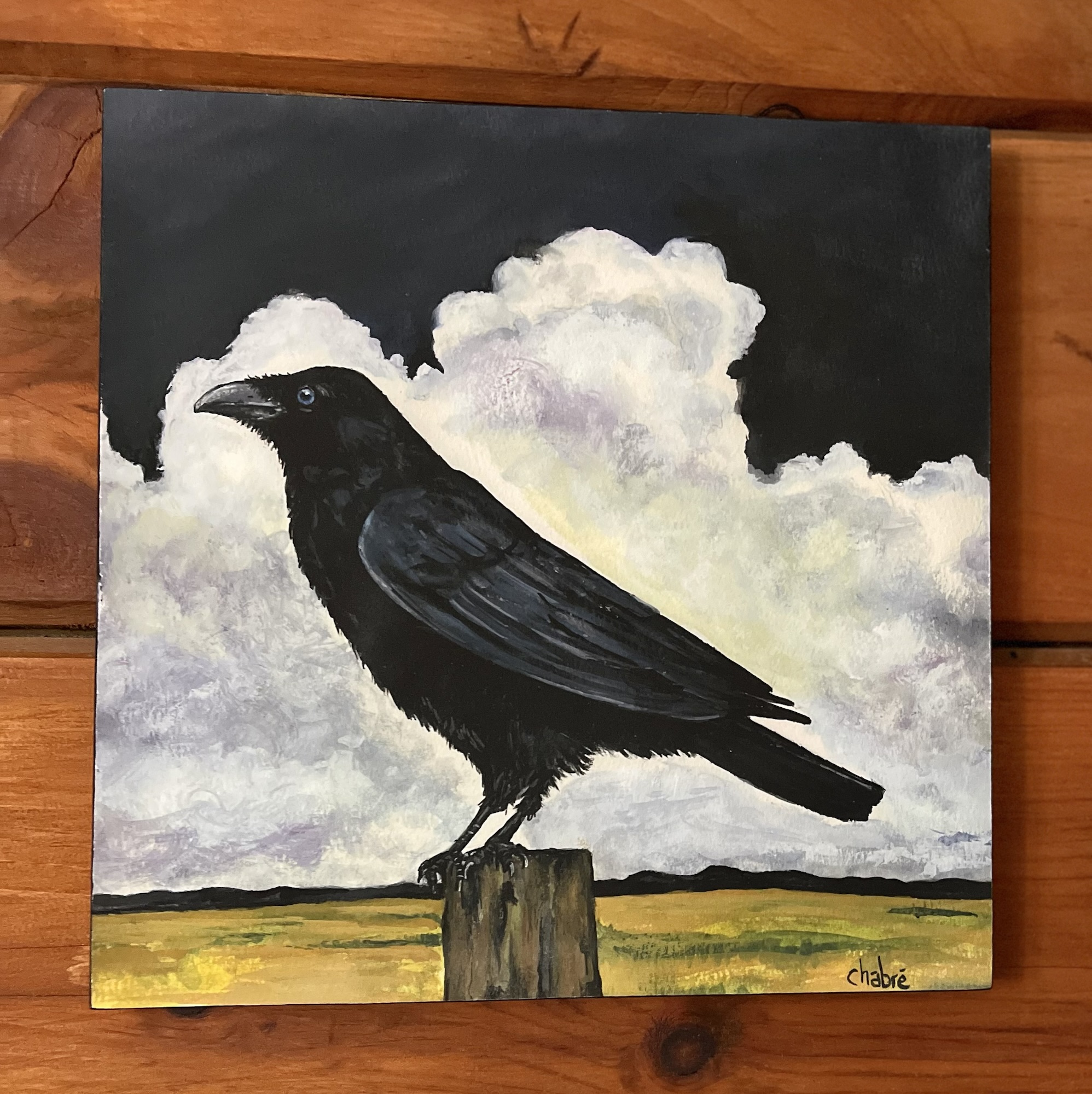 Mounted print of a crow on a wooden post with storm clouds, sold artwork by Riverbed Art.
