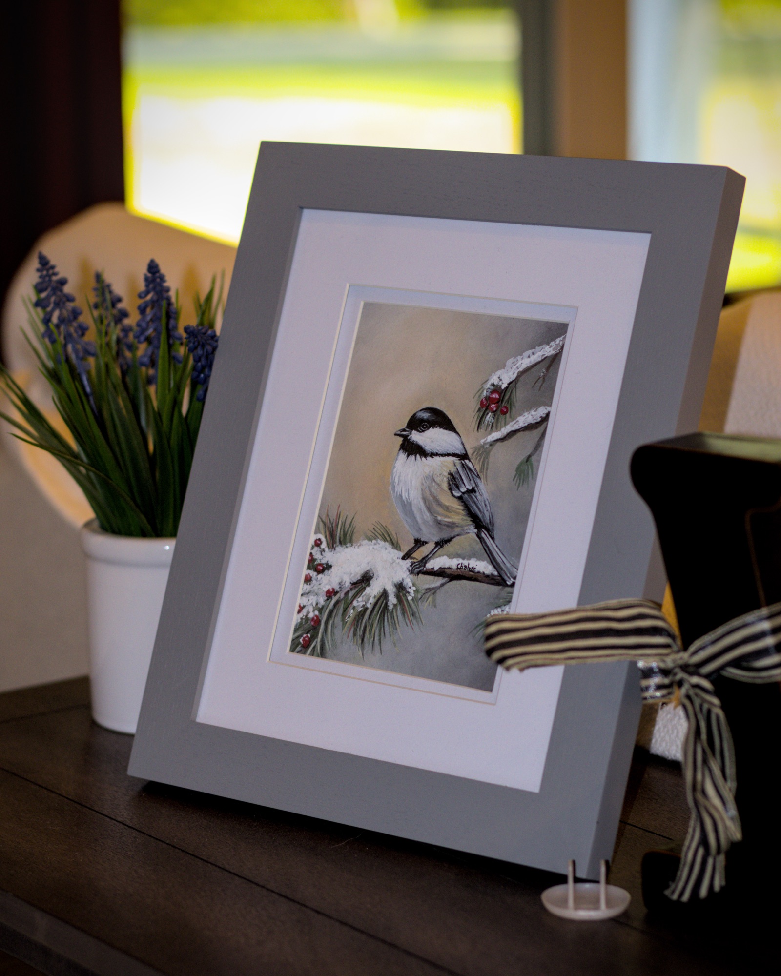 Original Riverbed Art winter chickadee watercolor and gouache artwork on display.