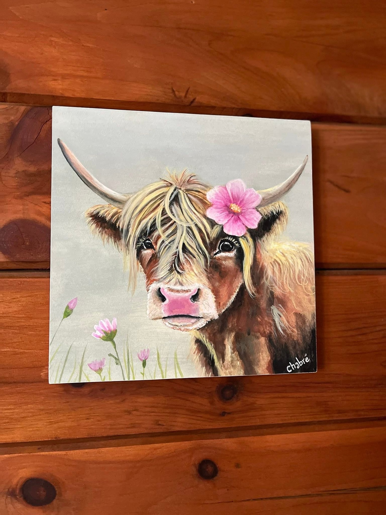 Mounted print of a Highland cow with pink flower, sold farmhouse artwork by Riverbed Art.