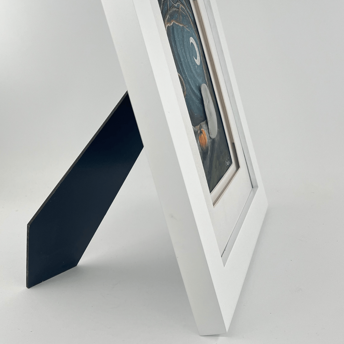 Side view of October Night Aroostook River Illustration framed in white wood with backing stand, showing its ready-to-display tabletop design.