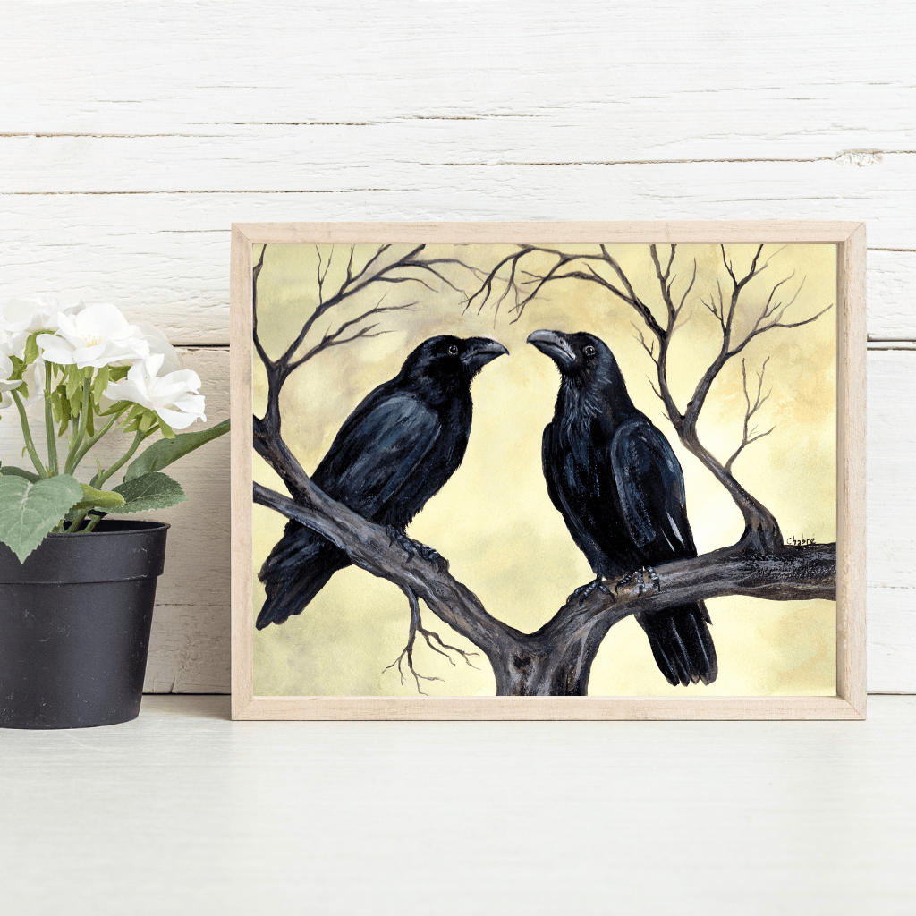 “The Couple” original crow art print by Riverbed Art shown in a natural wood frame on a tabletop