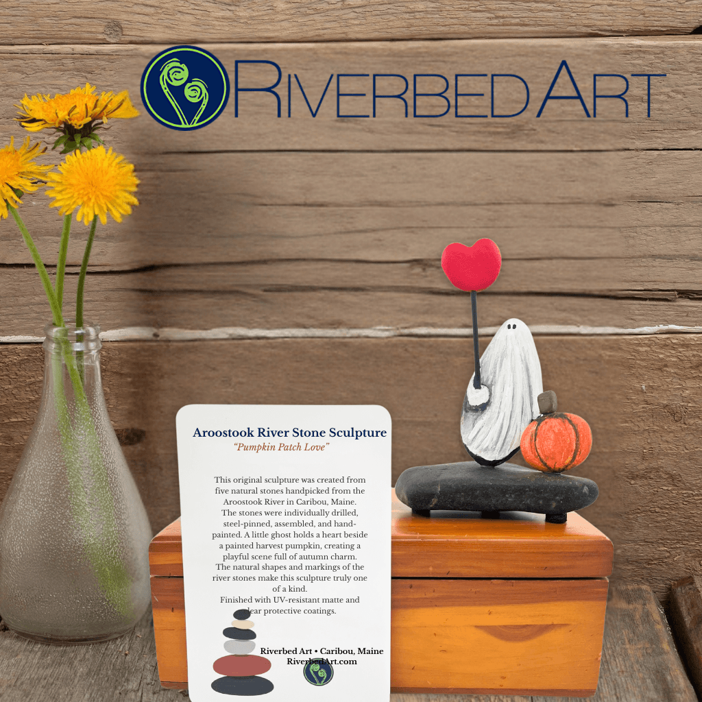 Riverbed Art promotional image of Pumpkin Patch Love stone sculpture with its information card beside yellow flowers.