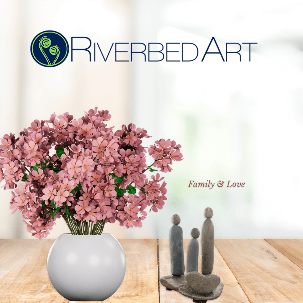 Family & Love river stone family sculpture displayed beside pink flowers