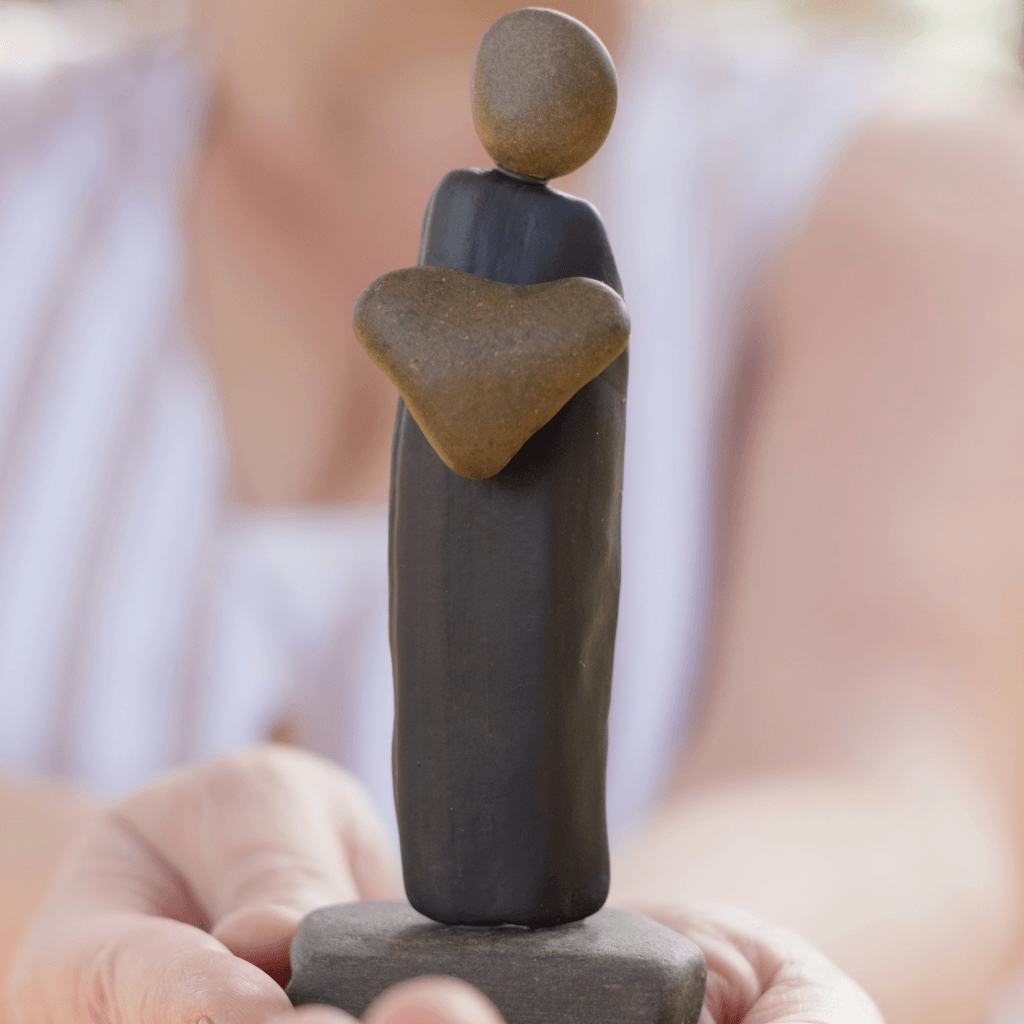 Close view of I Give You My Heart stone sculpture held in hands, showing the brown heart and gray stone body.