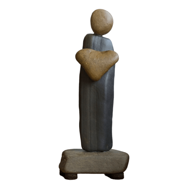 Aroostook River stone figure holding a brown heart against a long gray body on a stone base.