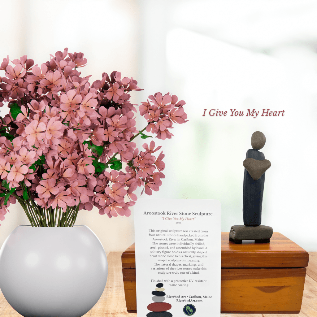 I Give You My Heart stone sculpture and information card beside pink flowers, with the artwork title above.