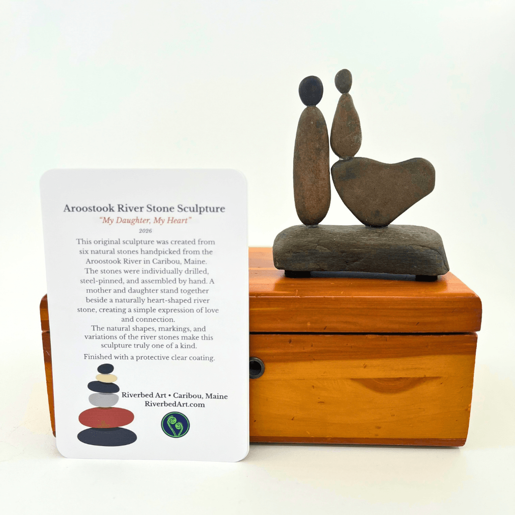 Back view of My Daughter, My Heart Aroostook River stone sculpture, showing two figures and a heart on a stone base.