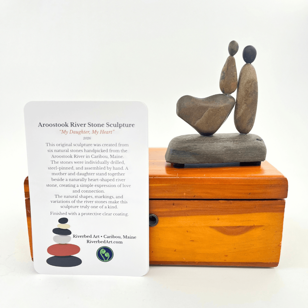 Alt text: Front view of My Daughter, My Heart river stone sculpture with mother and daughter figures, a natural stone heart and story card.