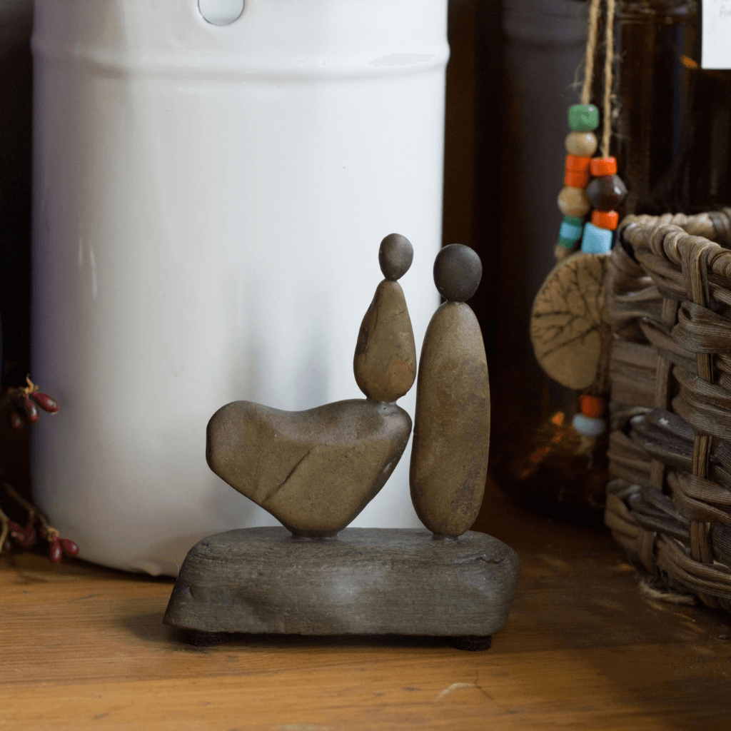 Close view of My Daughter, My Heart stone sculpture showing two figures, a naturally shaped heart and a stone base.
