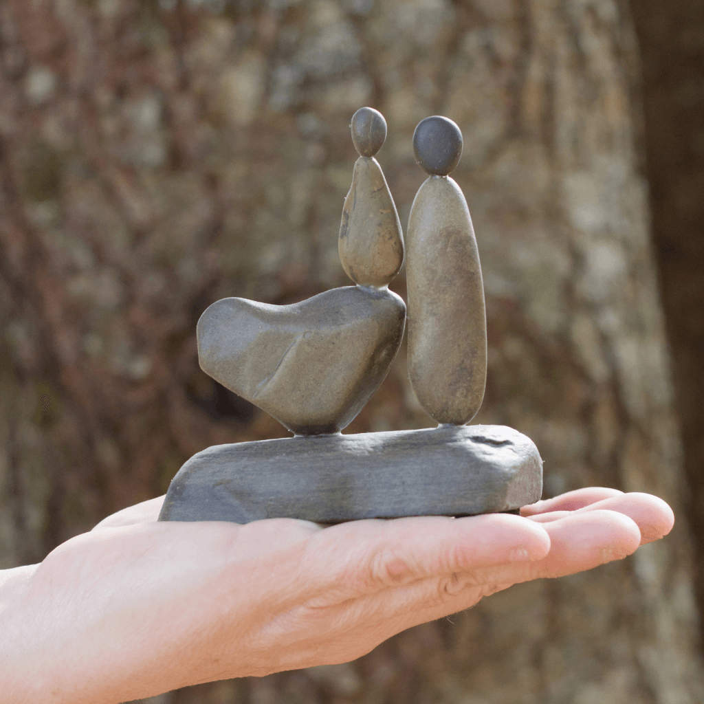 My Daughter, My Heart mother and daughter stone sculpture resting on an open palm outdoors to show its size.