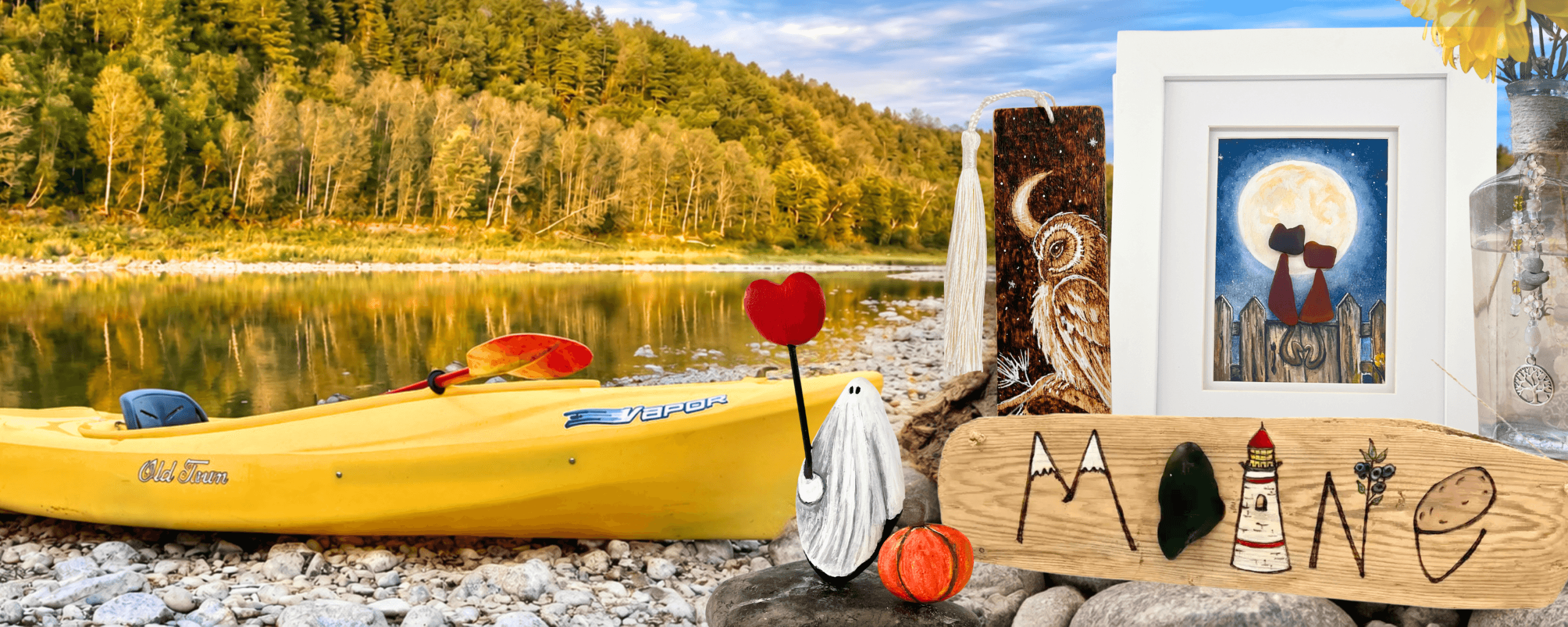 Riverbed Art handmade Maine artwork featuring Aroostook River stones, river glass, driftwood, framed art, and a yellow kayak by the river