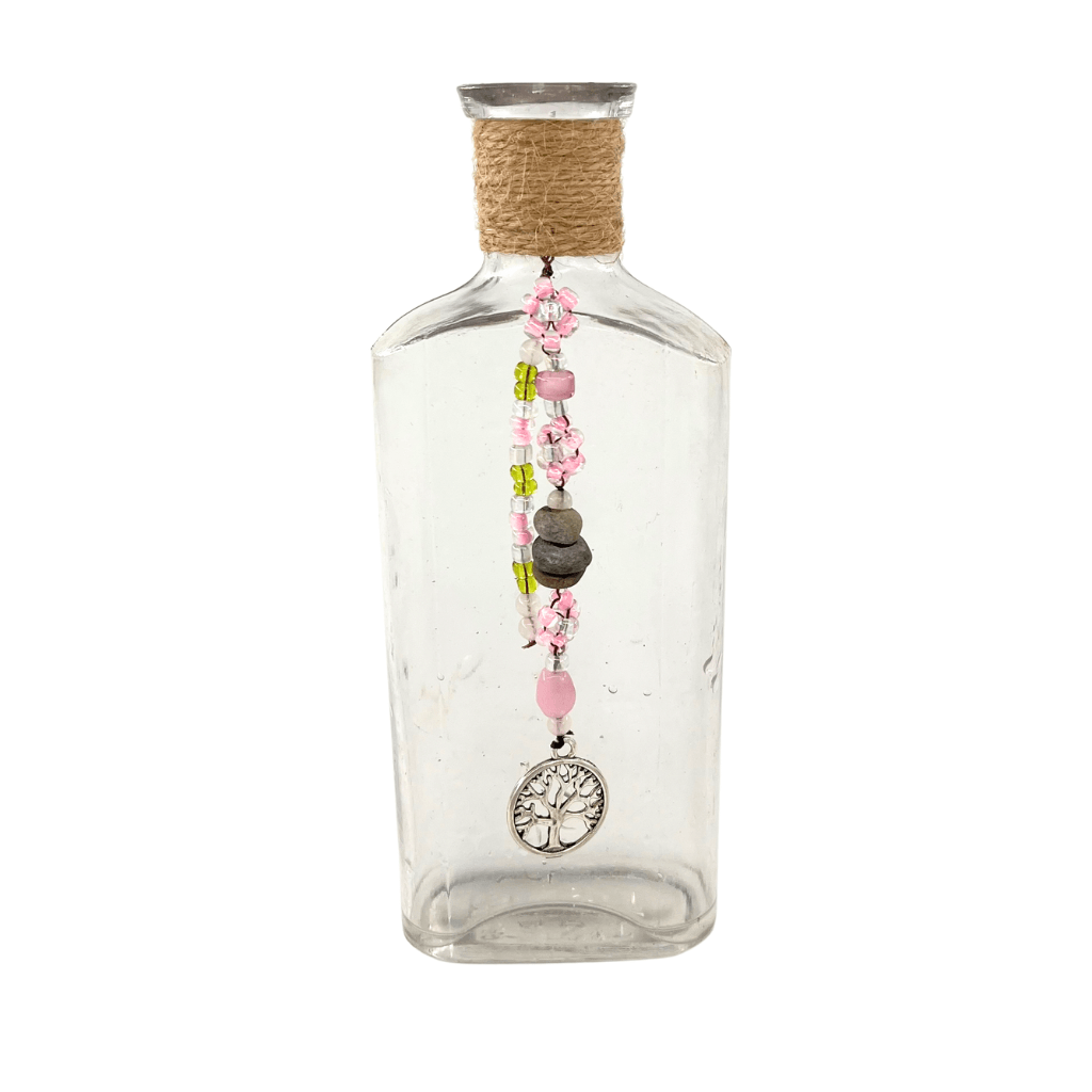 Upcycled vintage BEST bottle from the Aroostook River with stitched seed bead daisies, drilled river stones, pink and green glass beads, and a Tree of Life charm