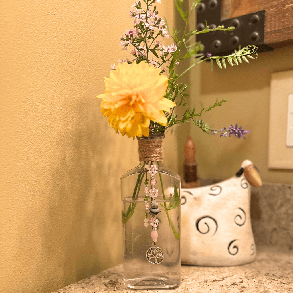 Vintage BEST bottle from the Aroostook River used as a flower vase with stitched seed bead daisies, drilled river stones, and Tree of Life charm