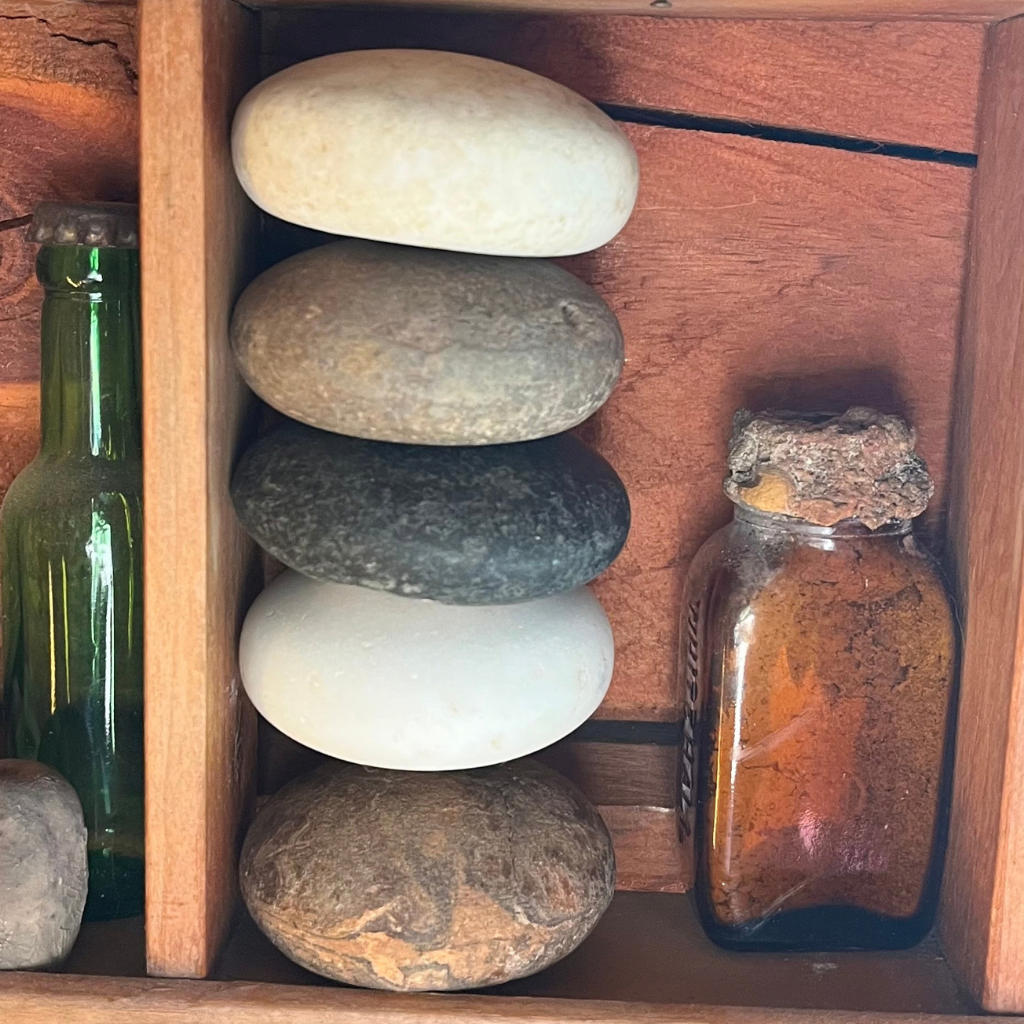 Five antique ceramic and porcelain doorknobs displayed on a shelf with other Aroostook River finds