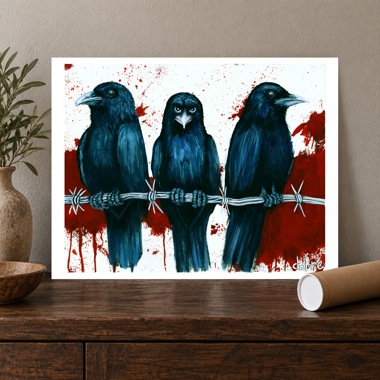 Murder crow artwork on a white bordered sheet displayed on a dark wood console beside a kraft mailing tube.