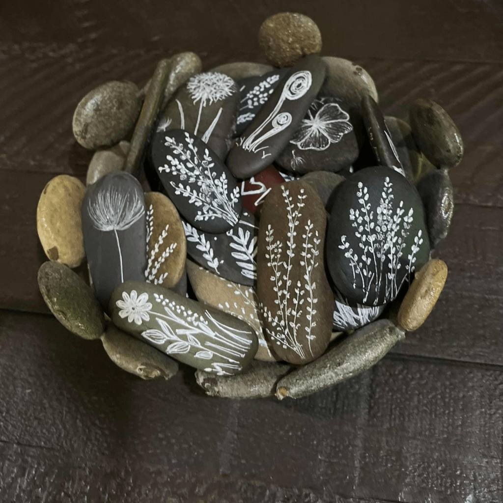 Collection of natural river stones illustrated with white flowers and botanical designs